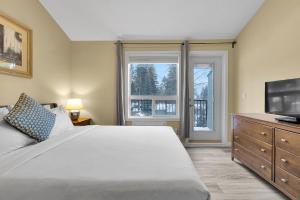 a bedroom with a large bed and a flat screen tv at banff woods lodge in Canmore