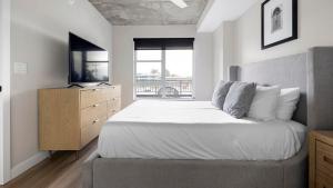 a bedroom with a bed and a dresser with a television at Landing Modern Studio Rooftop Lounge Gym in Englewood