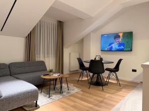 een woonkamer met een bank en een tv aan de muur bij Residence 33 in Sarajevo
