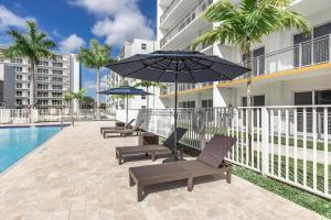 een patio met stoelen en een parasol naast een zwembad bij Landing Stunning 3BD Pool Gym in Naranja