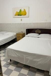 una camera da letto con due letti e un quadro di pere sul muro di Hotel Claveles Atlixco ad Atlixco