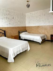 due letti in una camera d'albergo con lenzuola bianche di Hotel Claveles Atlixco ad Atlixco