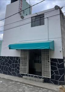 Un edificio bianco con un tendone blu sopra di Hotel Claveles Atlixco ad Atlixco