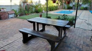 een houten bank naast een zwembad bij Waaigras in Brackenfell