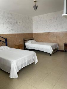 una stanza con due letti in una stanza di Hotel Claveles Atlixco ad Atlixco Altre 3 foto