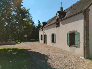 een gebouw met groene luiken voor de ramen en een oprit van grind bij Gîtes Le Gros Chêne in Meaucé