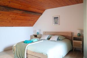 een slaapkamer met een groot bed met een houten plafond bij Gîtes Le Gros Chêne in Meaucé