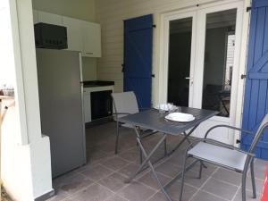 une cuisine avec une table, des chaises et un réfrigérateur dans l'établissement LE DOMAINE de L'HYLODE, à Sainte-Anne