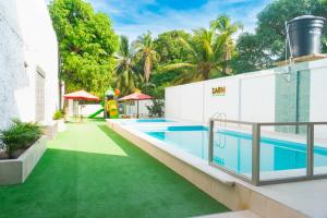 an outdoor swimming pool with green grass next to a building at ZABDI COVEÑAS in Coveñas