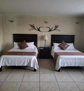 ein Schlafzimmer mit zwei Betten und einer Wand mit zwei in der Unterkunft Hotel Villalba in Comitán de Domínguez