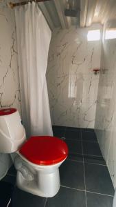 a toilet with a red seat in a bathroom at Finca Hotel Yamboró in Pitalito