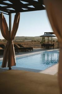 a swimming pool with an umbrella and tables and benches at Equ Hotel Boutique in El Porvenir