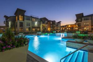 a swimming pool at night with buildings at Landing Incredible 1BD Pool Gym in Katy