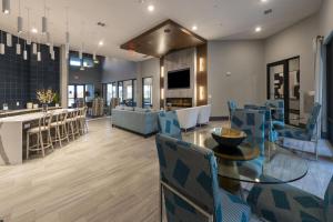 a dining room with a glass table and blue chairs at Landing Incredible 1BD Pool Gym in Katy
