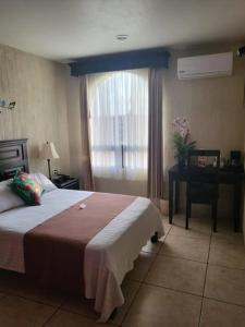 ein Schlafzimmer mit Bett, Schreibtisch und Fenster in der Unterkunft Hotel Villalba in Comitán de Domínguez
