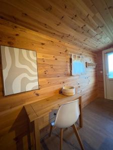 Cette chambre est dotée d'un mur en bois avec une table et une chaise. dans l'établissement Le Chalet des Pins - La Forge De Clermont, à Clermont