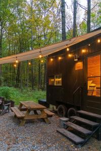 a black tiny house with a picnic table and lights at Postcard Cabins Eastern Catskills, Outdoor Collection by Marriott Bonvoy in Catskill