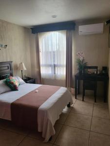 ein Schlafzimmer mit Bett, Schreibtisch und Fenster in der Unterkunft Hotel Villalba in Comitán de Domínguez