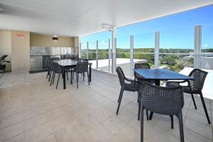 a dining room with tables and chairs and a kitchen at Ocean Views Retreat, Caloundra in Caloundra