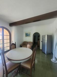 a dining room with a table and chairs and a refrigerator at Casa da Edna in Guarujá