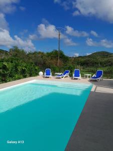 une piscine avec des chaises longues bleues dans l'établissement LE DOMAINE de L'HYLODE, à Sainte-Anne