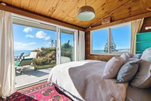 a bedroom with a large bed and a large window at Gorgeous Beach House in Pukehina +5 photos