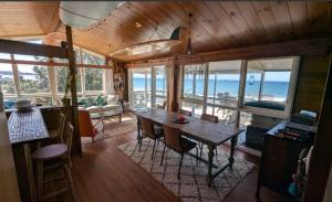 a living room with a table and chairs and the ocean at Gorgeous Beach House in Pukehina