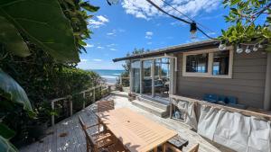 a patio with a table and chairs and a view of the ocean at Gorgeous Beach House in Pukehina