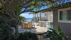 a patio with a table and chairs and the ocean at Gorgeous Beach House in Pukehina