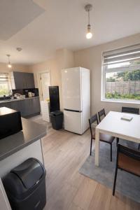 a kitchen with a white refrigerator and a table at The Stadium Rooms Elegant and Comfy Stay in London