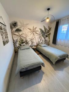 a bedroom with two beds and a mural of palm trees at Dom & Val in Tournan-en-Brie