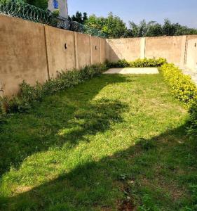 a yard with grass and a fence with a wall at Continental in Komé