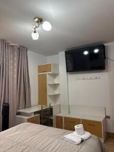 a bedroom with a bed and a desk with a television on the wall at Hospedaje Ariana in Supe