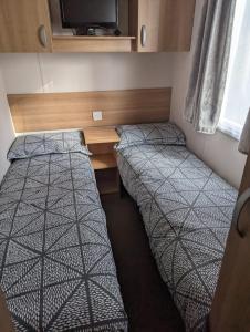 a small room with two beds and a desk at Denny's Holiday Homes in Blackpool