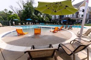 una piscina con sedie e ombrellone e tavolo e sedie di Landing Chic 2BD Gym Pool a Frederick