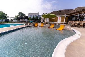 a swimming pool with yellow chairs and an umbrella at Landing Apartments - Prospect Hall in Frederick
