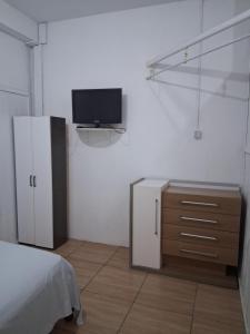 a bedroom with a bed and a tv on a wall at Kitnet Avenida in Imbituba