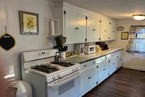 a kitchen with a stove and white cabinets at Sunset Cottage in Havana