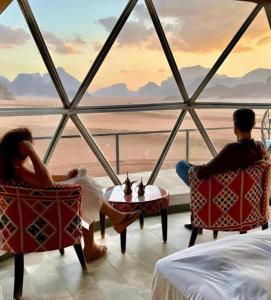 een stel zit in stoelen en kijkt uit over de oceaan bij Mars Camp, Lunar Space in Wadi Rum