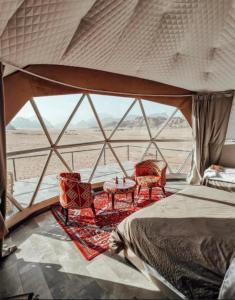 een slaapkamer met een bed, twee stoelen en een tafel bij Mars Camp, Lunar Space in Wadi Rum
