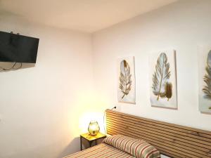 a bedroom with a bed and three pictures on the wall at H & L Fogar do Camiño in Padrón