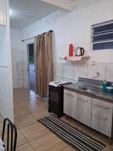 a kitchen with a sink and a stove in it at Kitnet Avenida in Imbituba