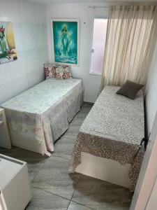 een kleine slaapkamer met twee bedden en een raam bij Arembepe Vilage Duplex in Camaçari