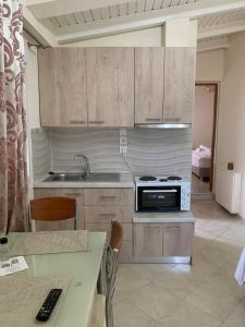 une cuisine avec des armoires en bois, un évier et une cuisinière dans l'établissement vasiliki's Apartments, à Dhímitra