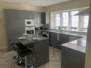 a kitchen with gray cabinets and a island with a bar at Modern Comfort for Longer Stays in Bury, 2-Bedrooms in Walmersley +8 photos