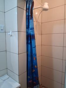 a shower in a bathroom with a blue shower curtain at Kitnet Avenida in Imbituba +7 photos