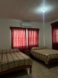 2 letti in una camera con tende rosse di Casa de Playa Elsa a La Vigueta