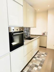 a white kitchen with white cabinets and a sink at The Twins Suite & Hub in Monza +15 photos