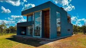 a blue house with large windows on a field at Casa Bela Vista do Cerrado in Samambaia