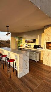 a kitchen with a counter with red chairs in it at Casa Bela Vista do Cerrado in Samambaia